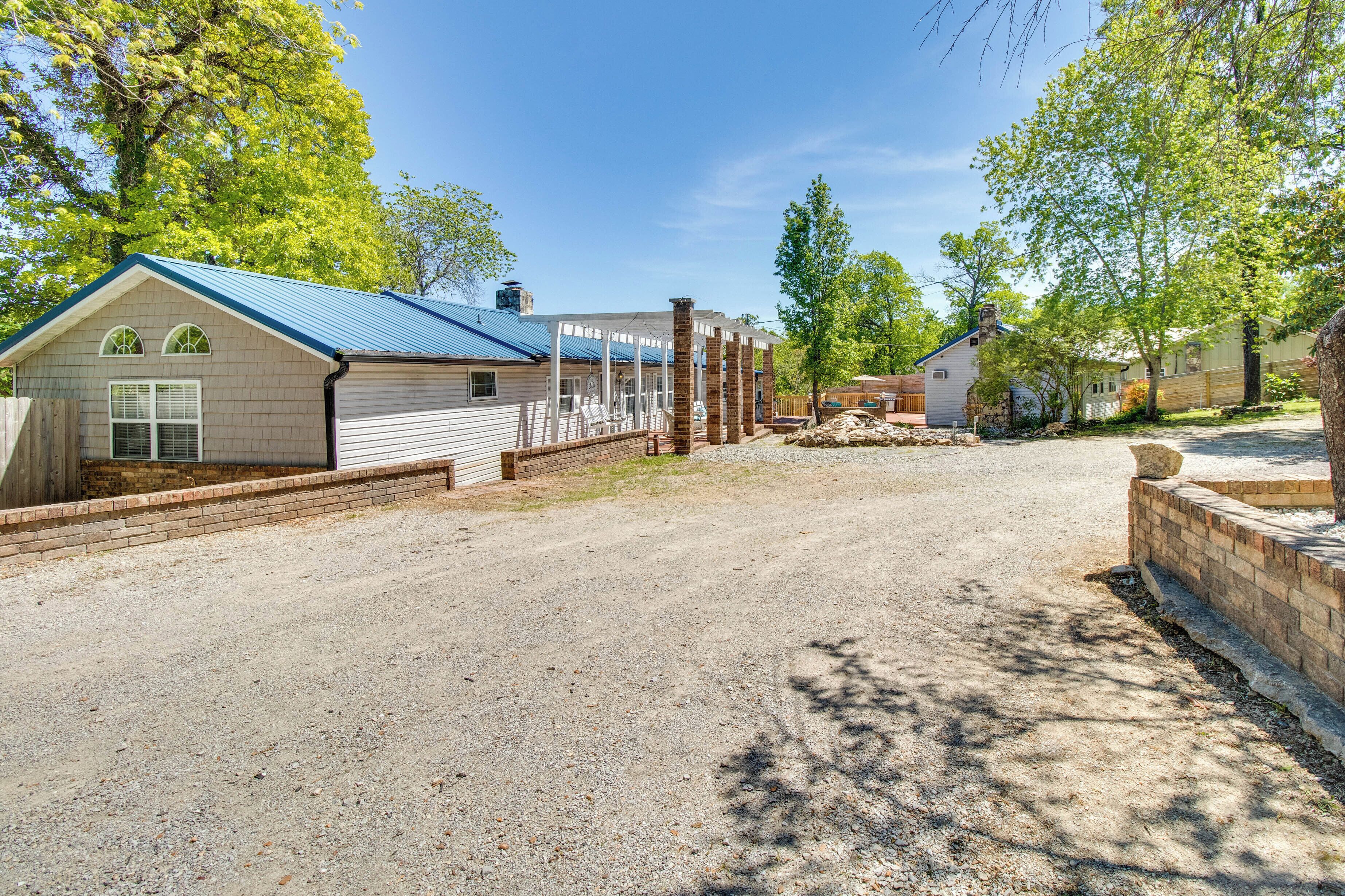 A residential property with a gravel driveway, a covered patio, and a house with a blue roof.