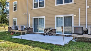 A two-story building with a flat roof, large windows, and a covered patio area with outdoor air conditioning units. - Cozy Cape Charles Apartment: Walk to Beaches! (Cape Charles)