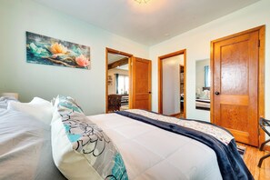 A bedroom with a bed, a wooden door, and a painting on the wall. - Charming Eagle Grove Farmhouse w/ Patio! (Eagle Grove)