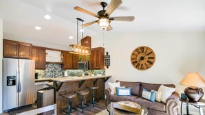 Eine moderne Küche mit Holzausstattung, einem Edelstahlkühlschrank und einer Bar mit Barhocker.