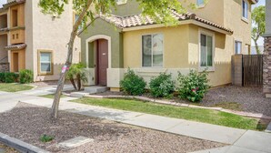 A residential building with a beige facade, a tiled roof, and a front yard with a tree and shrubs. - Welcoming Phoenix Home w/ Community Amenities! (Phoenix)