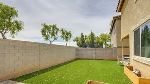 A backyard with a green lawn, a brick wall, and a wooden deck. - Welcoming Phoenix Home w/ Community Amenities! (Phoenix)