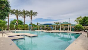 A swimming pool with a green-roofed pavilion, palm trees, and a clear sky. - Welcoming Phoenix Home w/ Community Amenities! (Phoenix)