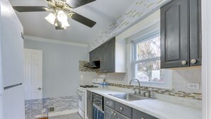 A kitchen with grey cabinets, a white countertop, a window, and a ceiling fan. - ~ 20 Mi to Manhattan: Quaint Clifton Home! (Clifton)