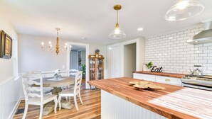 A kitchen with a wooden island, white cabinetry, and a brick backsplash. - Quiet Waterfront Home: Ideal Maine Escape! (Bass Harbor)