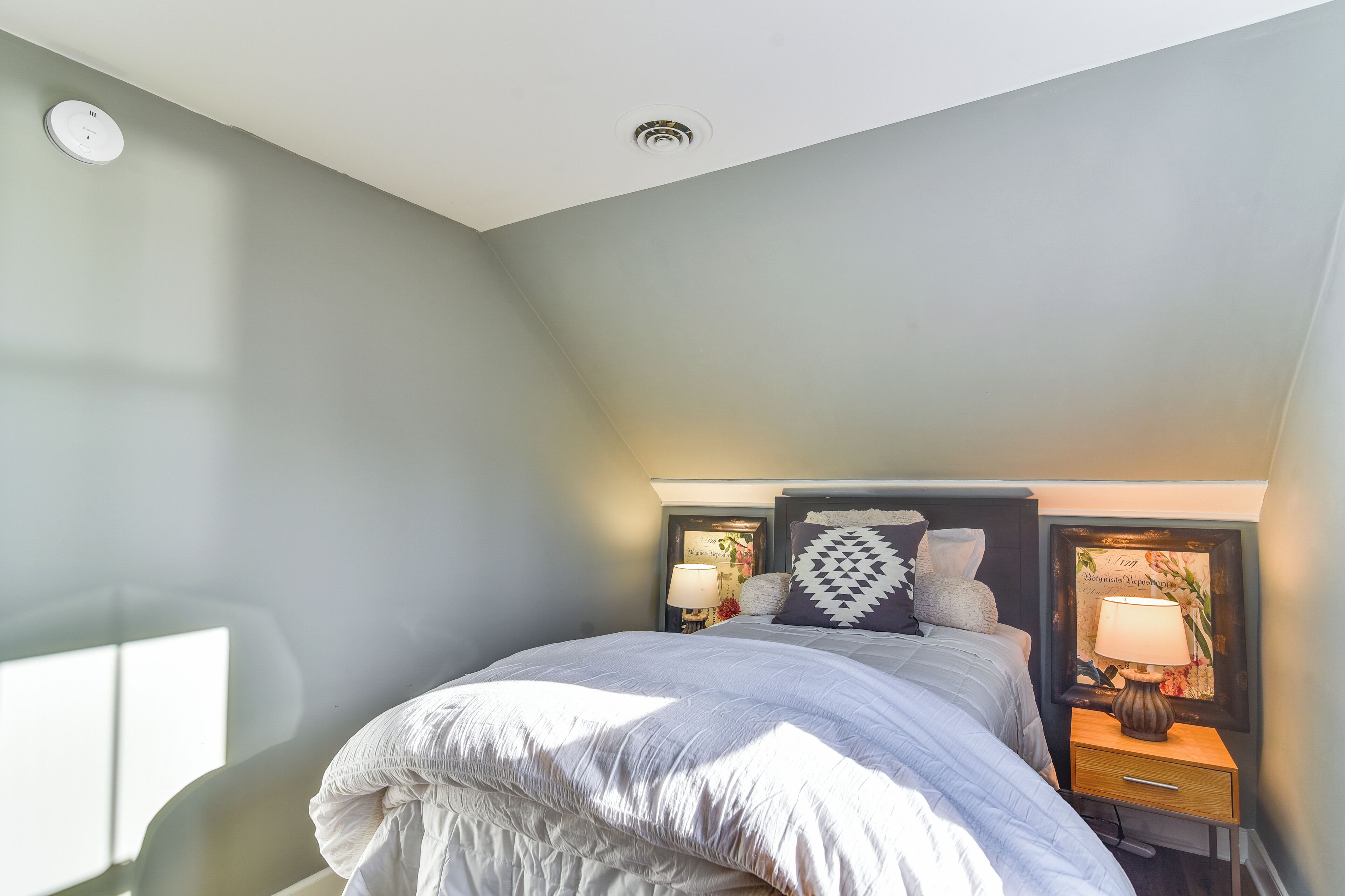 A bedroom with a bed, nightstands, and a wall-mounted lamp.