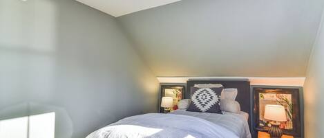 A bedroom with a bed, nightstands, and a wall-mounted lamp.