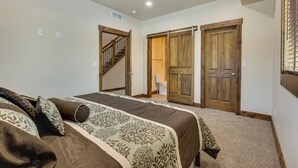 A bedroom with a large bed, a wooden door, a staircase, and a closet. - ~ 3 Mi to Granby Ranch: Spacious Cabin Home! (Granby)