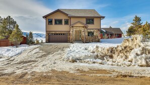 A two-story house with a stone facade, a garage, and a driveway leading to a snow-covered area. - ~ 3 Mi to Granby Ranch: Spacious Cabin Home! (Granby)