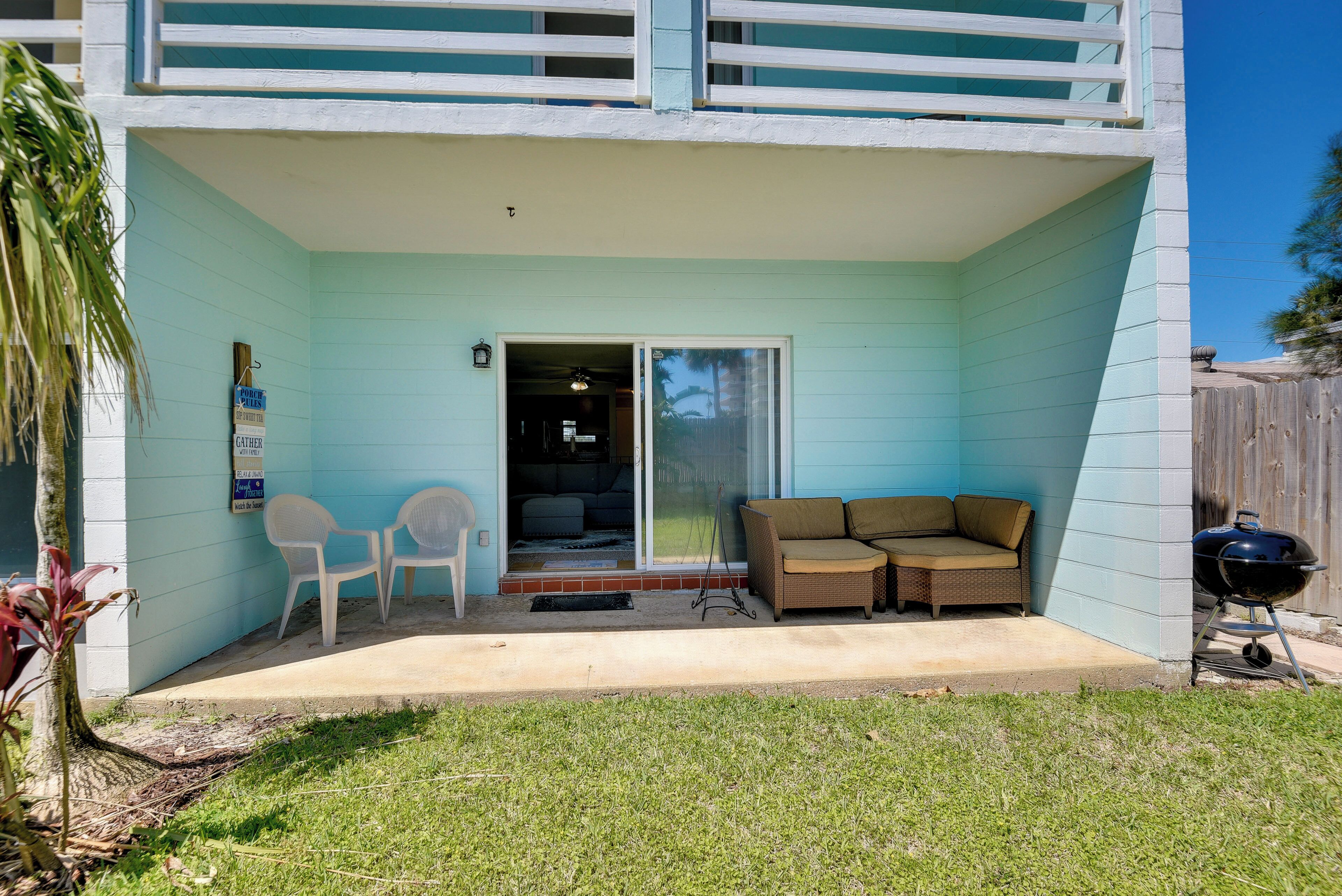 A house with a covered patio, a sliding glass door, a barbecue grill, and a small outdoor seating area with two chairs.