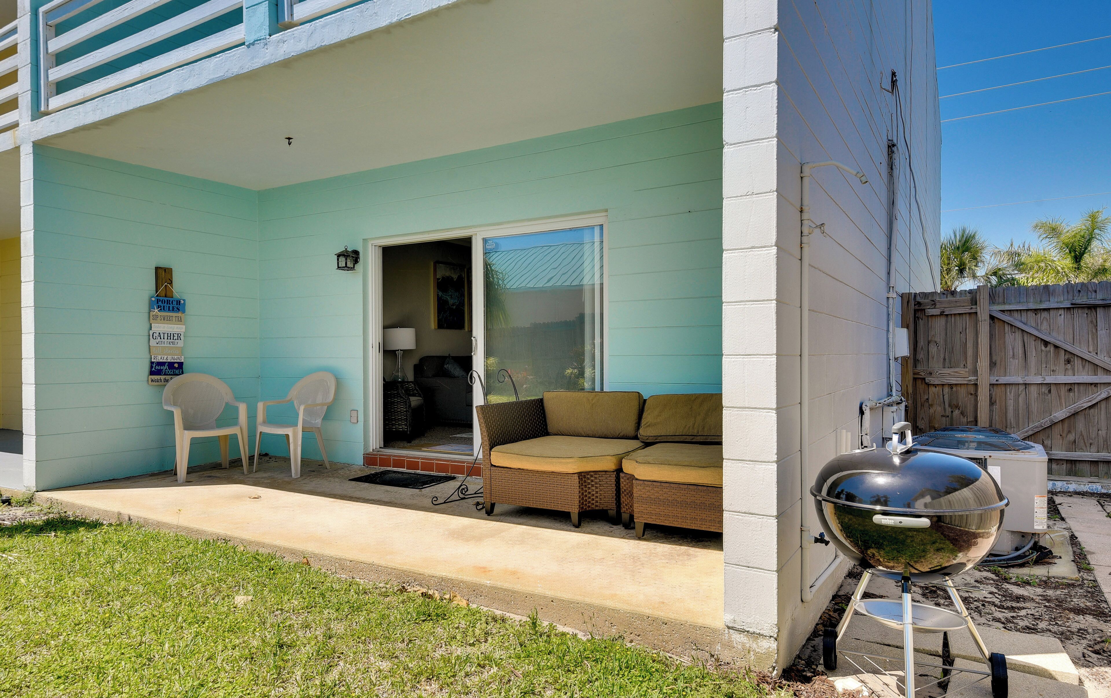 A covered patio with outdoor furniture, a grill, and a sign with family-oriented messages.