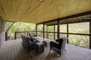 A covered outdoor seating area with wicker furniture and a view of a forested landscape. - Ski, Hike & Relax: Beech Mtn Gem w/ Sweeping Views (Banner Elk)
