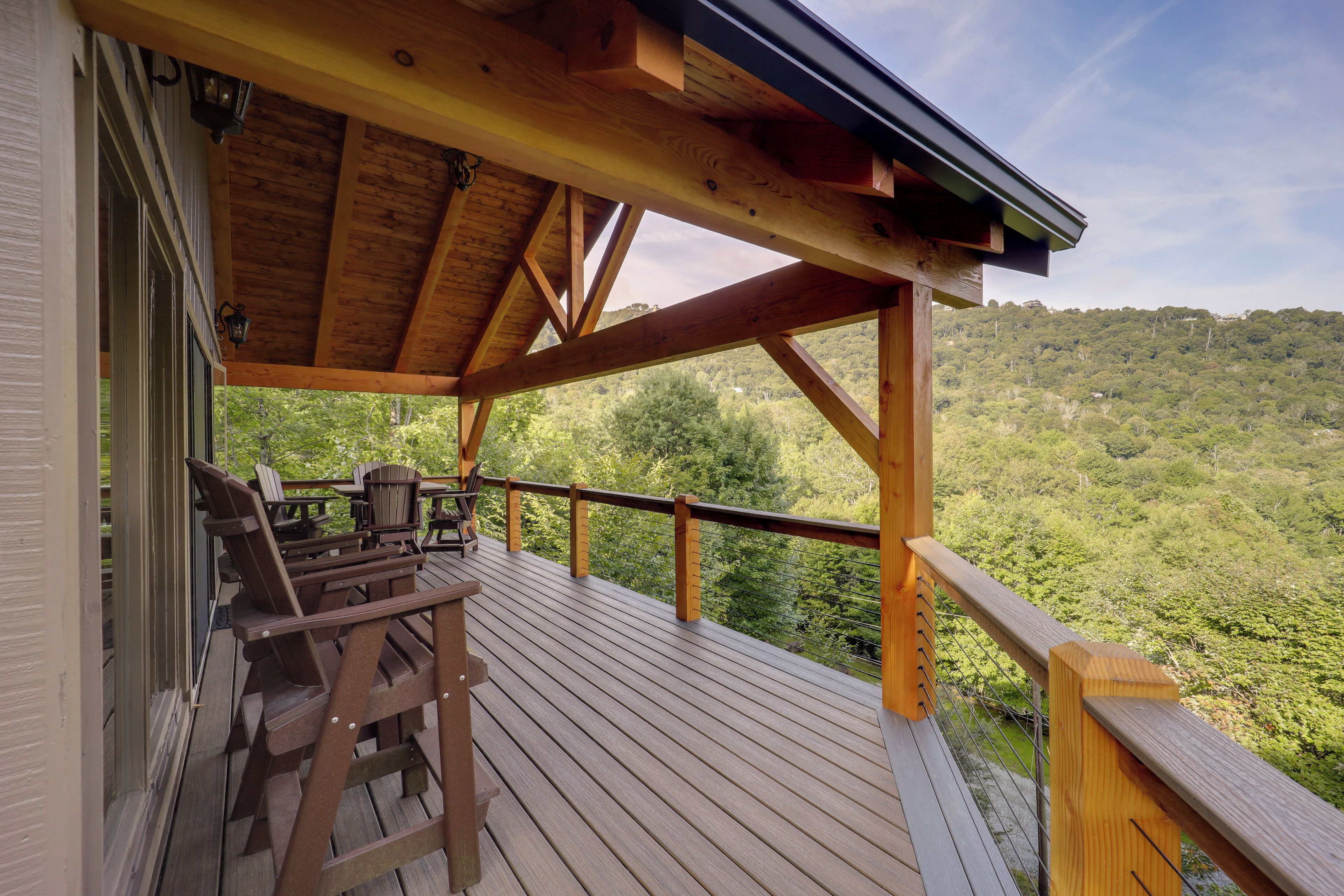 A wooden deck with a view of a forested hillside.