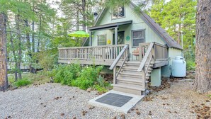 A cabin with a wooden deck, a covered porch, and a staircase leading to the entrance. - Deck & Grill: A-frame Cabin in Munds Park! (Munds Park)