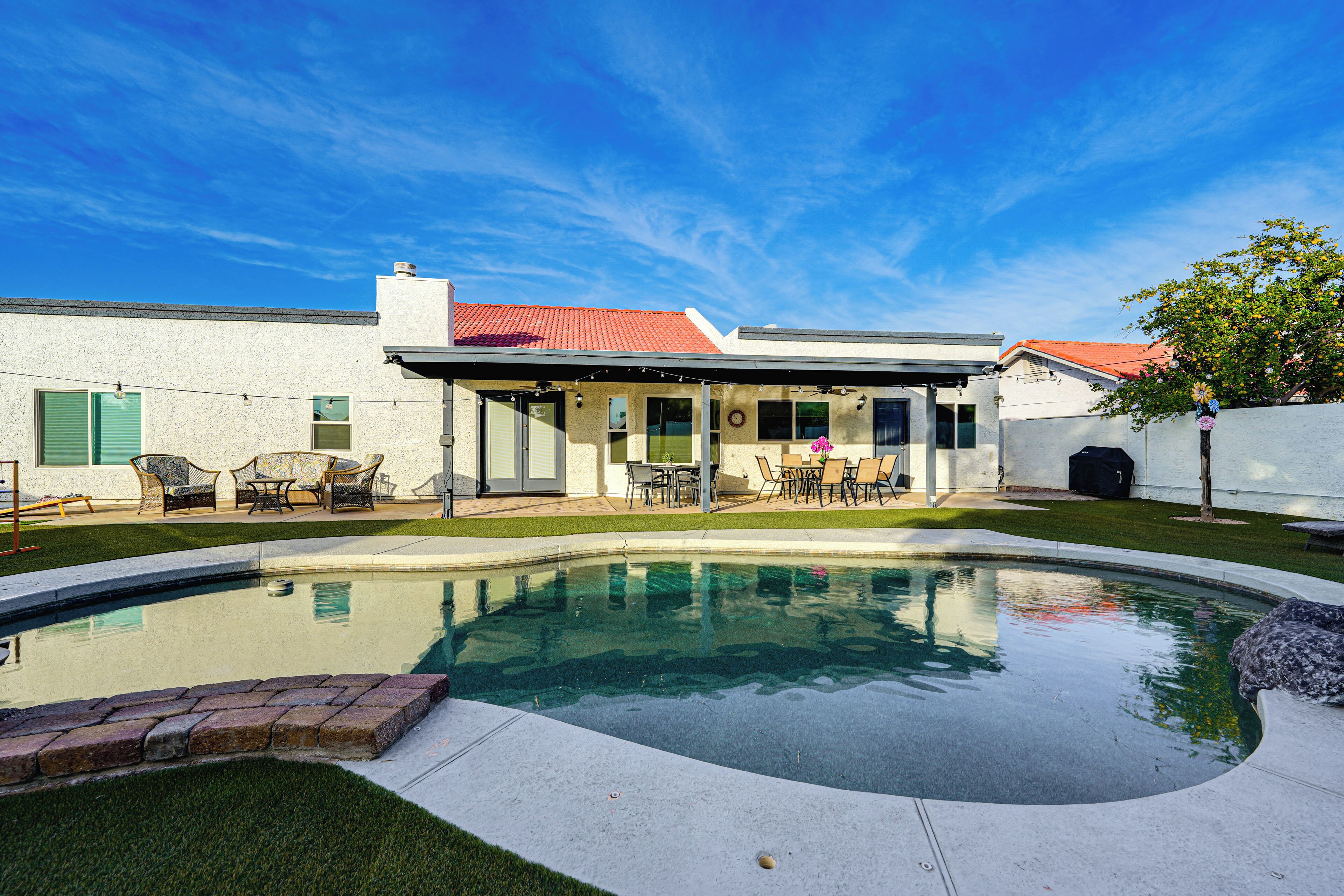 A modern house with a swimming pool, outdoor furniture, and a covered patio area.