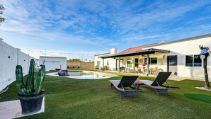 A backyard with artificial grass, two lounge chairs, a small pool, and a cactus plant. - Pool, Putting Green & Games: Chandler Home! (Chandler)