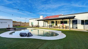 A modern house with a swimming pool, patio furniture, and a well-maintained lawn. - Pool, Putting Green & Games: Chandler Home! (Chandler)