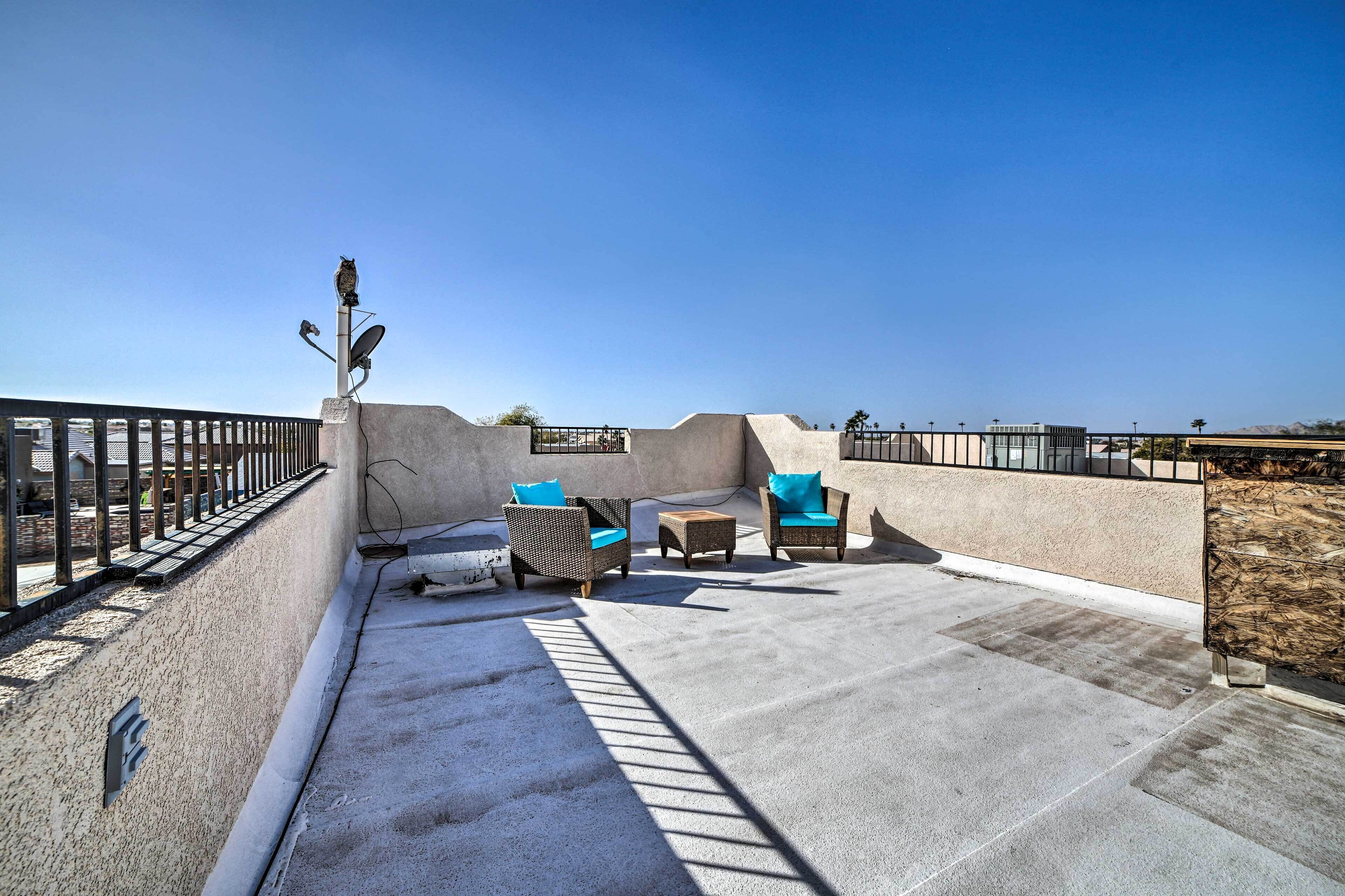 Une terrasse sur le toit, aménagée avec du mobilier d’extérieur, une antenne parabolique et un ciel dégagé.