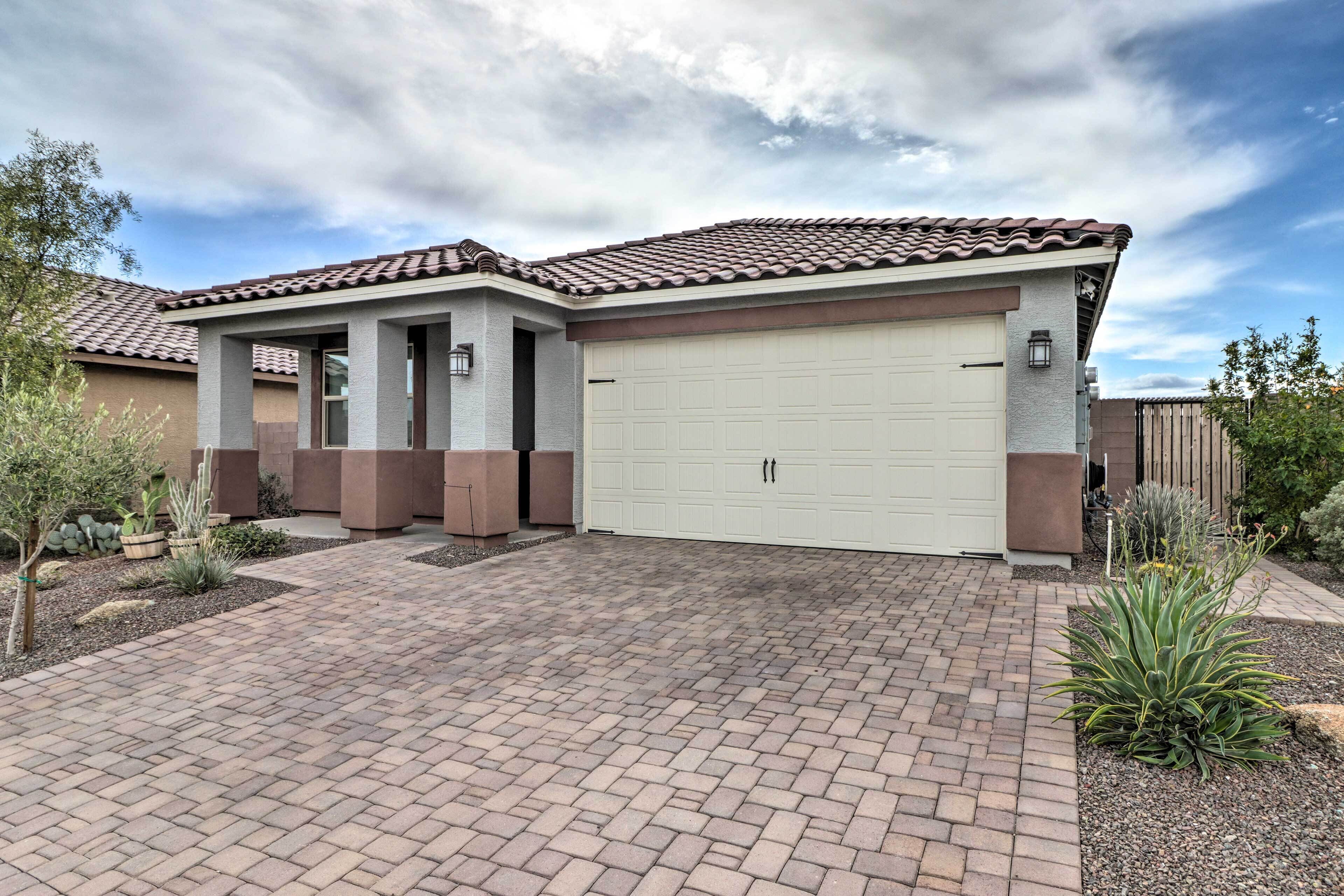 A two-story house with a tiled roof, a garage, and a paved driveway.
