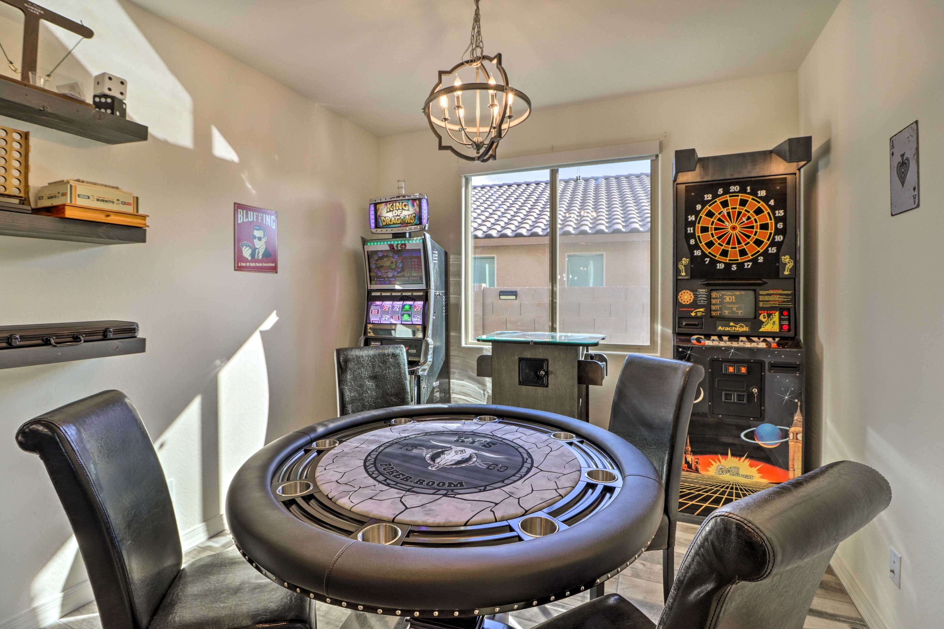 A room with a dartboard, a table with a circular design, and arcade games.