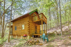 Une cabane en bois dotée d’un balcon, entourée d’arbres.