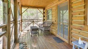 Eine Holzhütte mit Veranda, Korbmöbeln und einer Fußmatte.