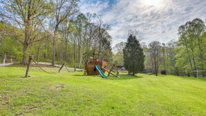 Ein Spielplatz mit Rutsche und Klettergerüsten in einer grünen Parkanlage.