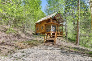 Une cabane en bois dotée d’un balcon, entourée d’arbres.