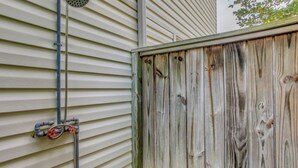 A wooden fence with a window, a metal pipe, and a hose attached to the wall.