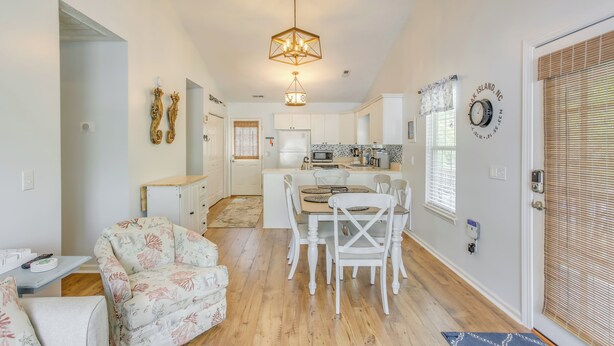 A spacious kitchen with white cabinets, a dining area with white chairs, and a central island.