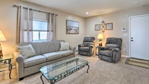 A living room with a sofa, two armchairs, a glass coffee table, a lamp, and a painting on the wall. - Waterfront East China Home w/ Dock & Patio! (East China)