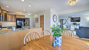 A modern kitchen with wooden cabinets, a central island, and a dining area with a wooden table and chairs. - Waterfront East China Home w/ Dock & Patio! (East China)