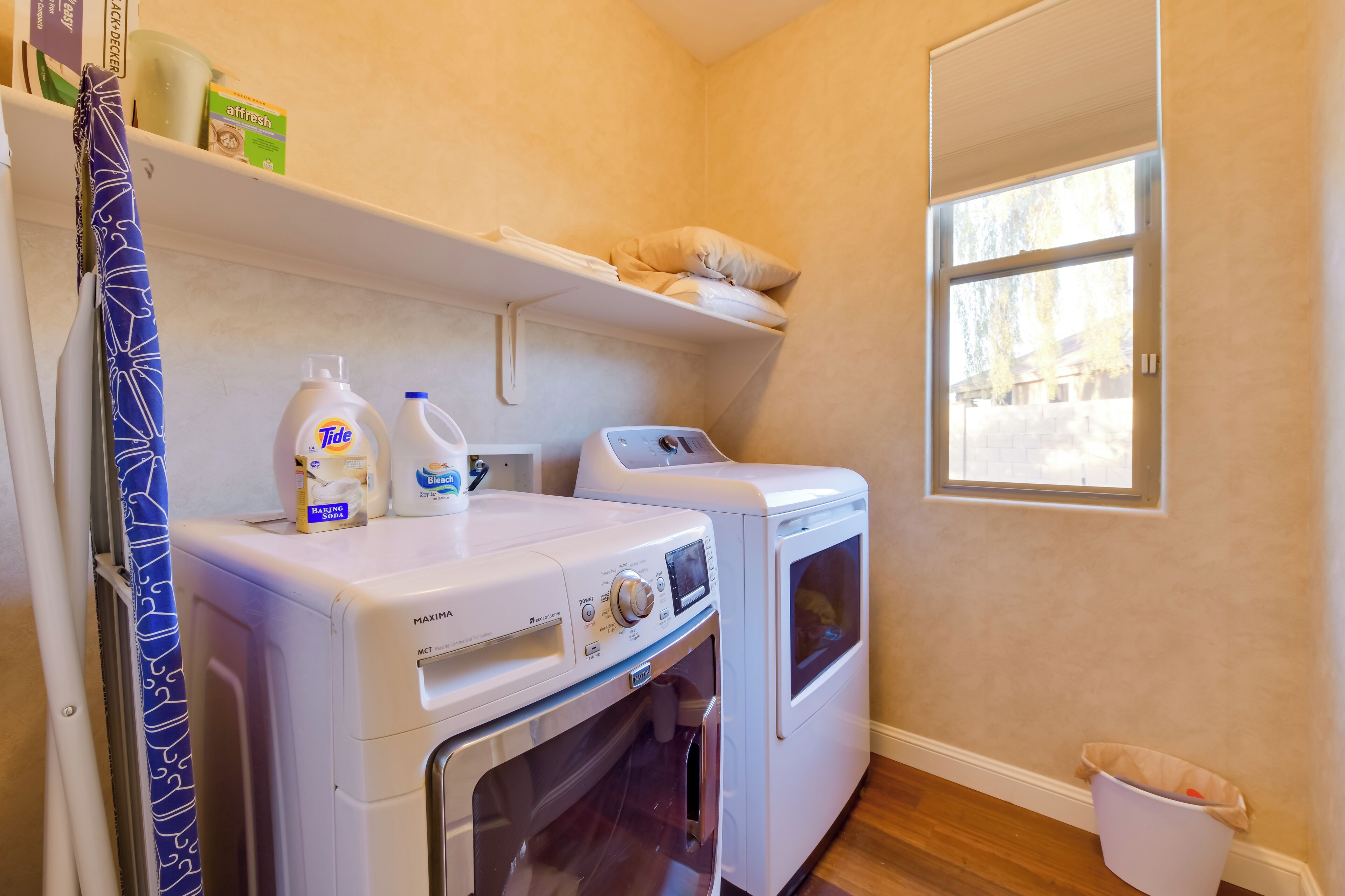 A laundry area with two washing machines, a drying rack, and a window.