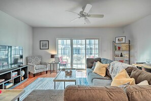 A modern living room with a sofa, armchair, coffee table, and bookshelf. - Patio & Pool Access: Rehoboth Beach Retreat (Rehoboth Beach)