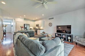 A modern living room with a grey sofa, a coffee table, and a TV stand with a flat-screen TV. - Patio & Pool Access: Rehoboth Beach Retreat (Rehoboth Beach)