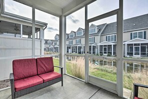 A covered patio with a wicker sofa and a view of a row of townhouses. - Patio & Pool Access: Rehoboth Beach Retreat (Rehoboth Beach)