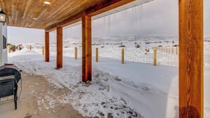 Un espace extérieur abrité avec des poutres en bois, un paysage enneigé et une zone délimitée par une clôture.