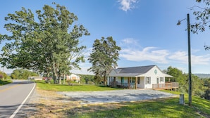 A small, single-story house with a porch and a fenced yard. - Beautiful Views & Gas Grill: Sparta Getaway! (Sparta)
