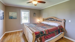 A bedroom with a wooden bed, a ceiling fan, a window, and a wall-mounted light. - Beautiful Views & Gas Grill: Sparta Getaway! (Sparta)