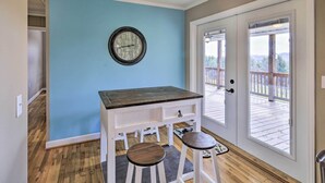 A kitchen with a blue wall, wooden floor, a clock, and a door leading to a deck. - Beautiful Views & Gas Grill: Sparta Getaway! (Sparta)