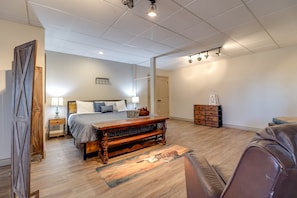 Une chambre à coucher avec un lit en bois, un banc, une commode et une porte.
