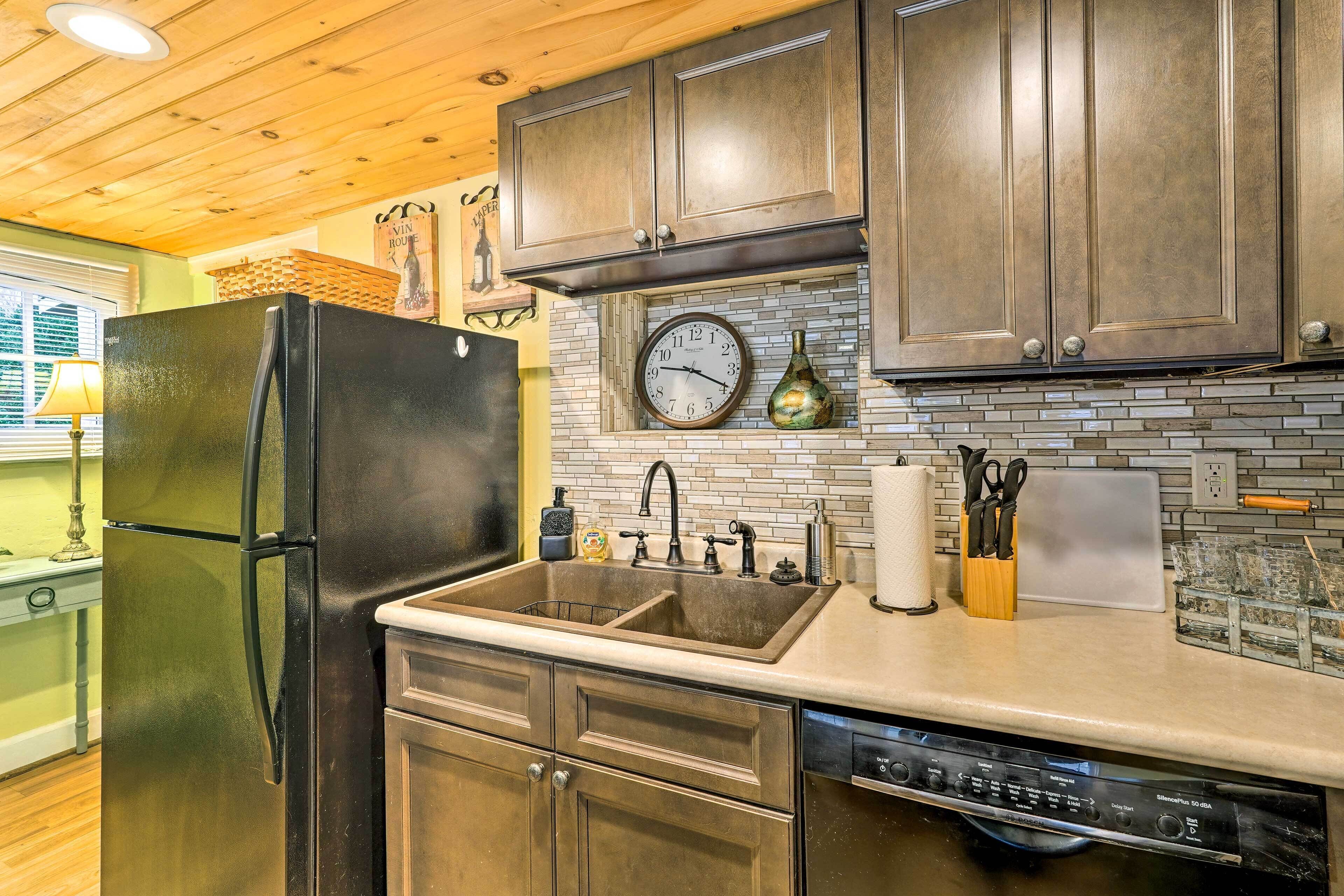 A kitchen with dark wooden cabinets, a black refrigerator, a double sink, and a clock on the wall.