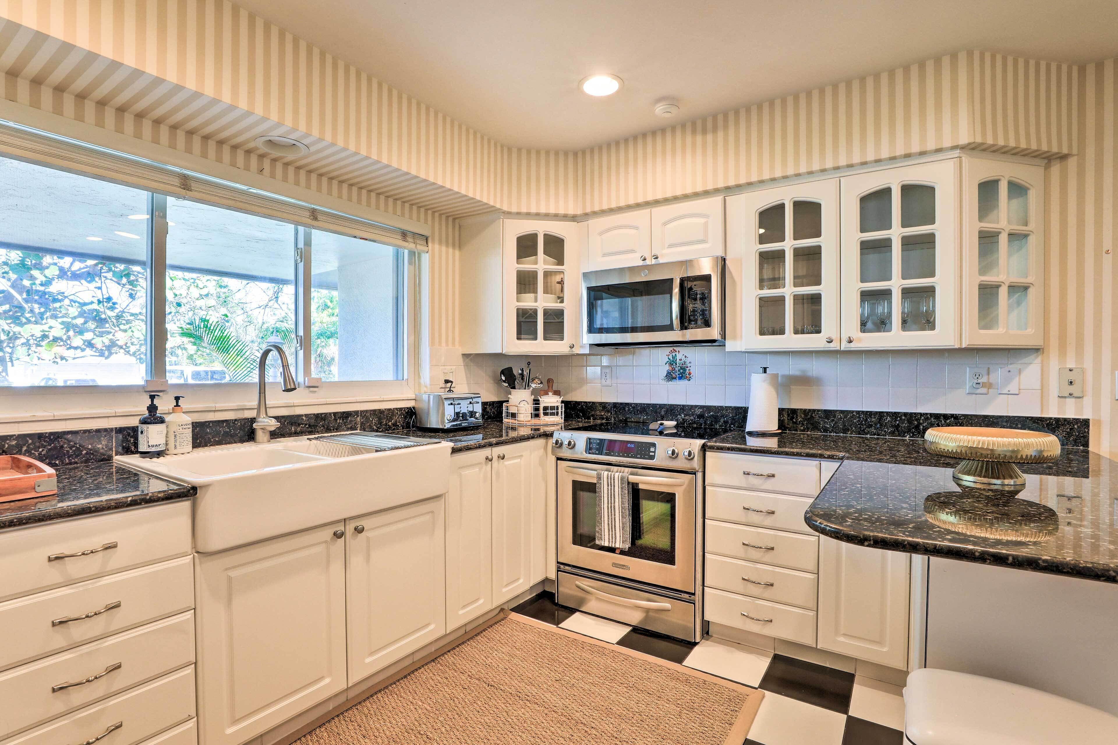 A modern kitchen with white cabinetry, a black and white checkered floor, and a large window providing natural light.