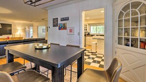 Un coin repas avec une table et des chaises en bois foncé, un sol à carreaux noirs et blancs et une porte blanche avec des panneaux de verre.