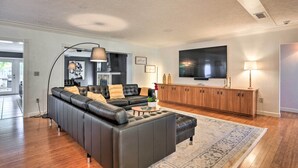 Un salon moderne avec un canapé en cuir, une table basse et un téléviseur fixé au mur.
