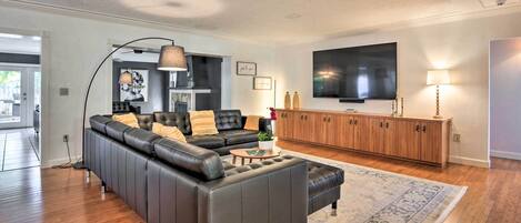 Ein modernes Wohnzimmer mit einer Ledersofa, einem Couchtisch und einem an der Wand befestigten Fernseher.