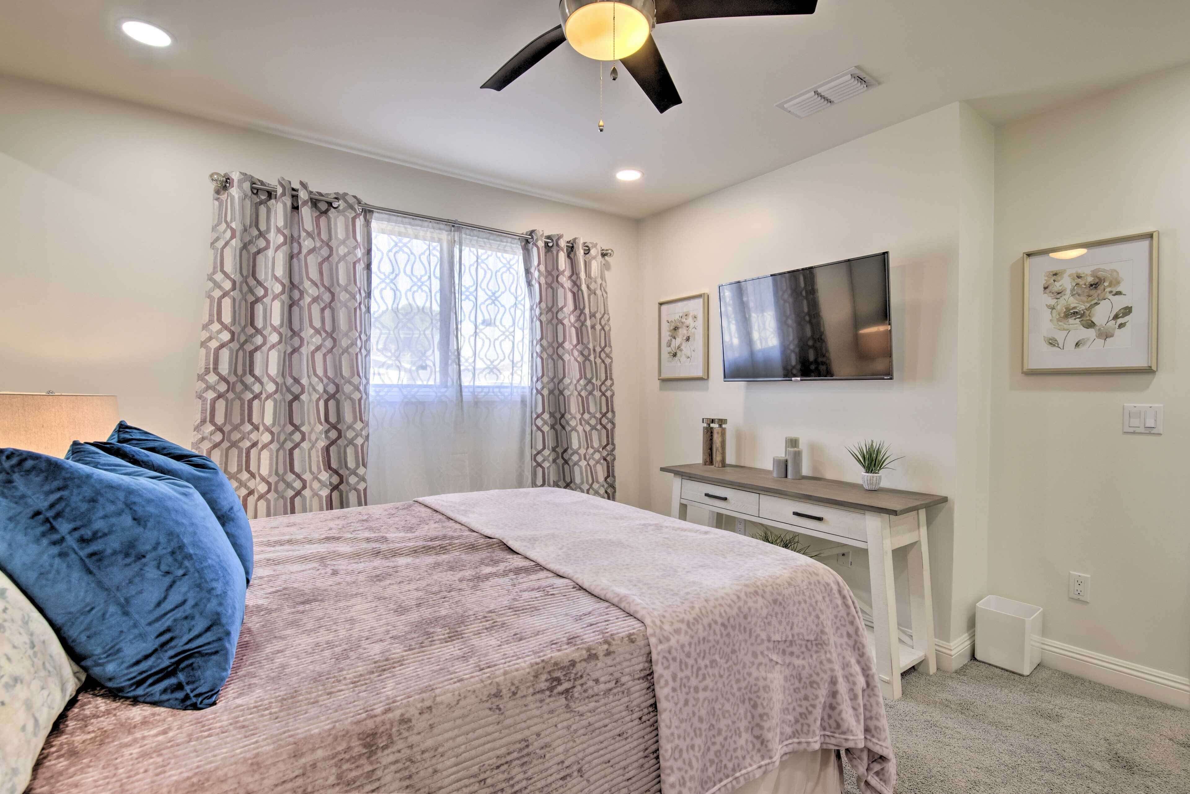 Ein Schlafzimmer mit Bett, Schreibtisch, Fernseher und Deckenventilator.