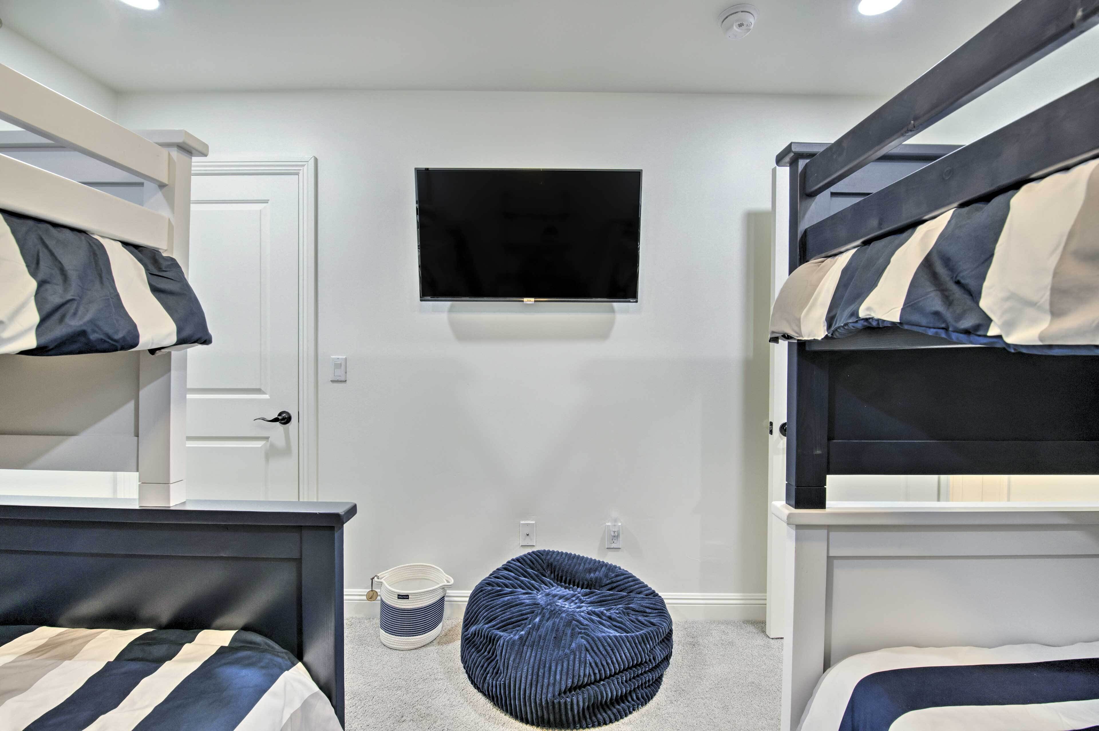 A room with bunk beds, a television, a bucket, and a bean bag chair.