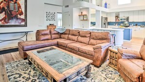 A spacious living room with a large brown leather sectional sofa, a glass-top coffee table, and a patterned rug. - Pool, BBQ & Fire Pit: Family Home in Cave Creek (Cave Creek)