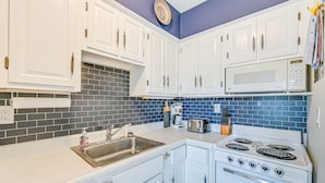 A kitchen with white cabinets, a microwave, a stove, and a sink. - Marco Island Condo ~ 1 Mi to the Beach! (Marco Island)